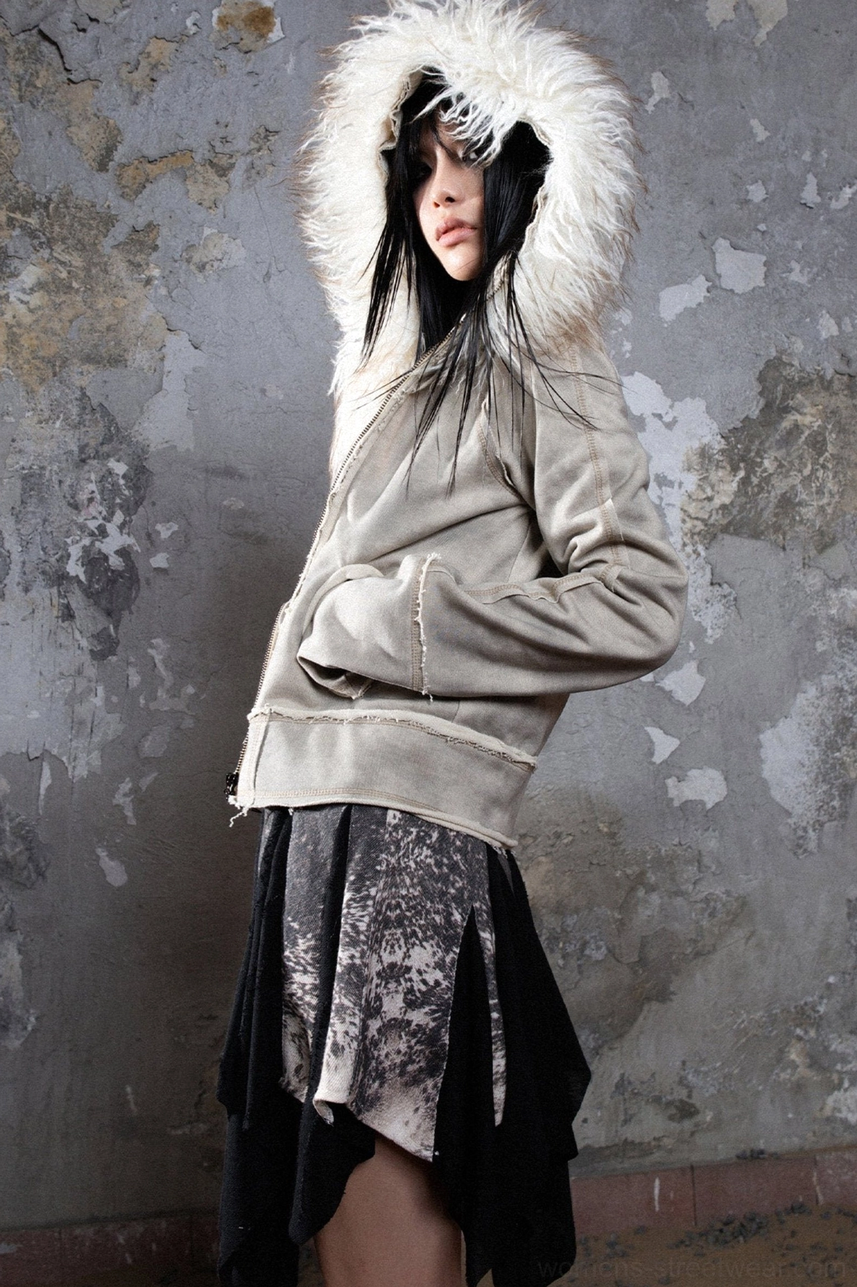 Gray faux fur hooded zip jacket three-quarter profile with half-open zipper, fluffy trim, and layered dark skirt styling
