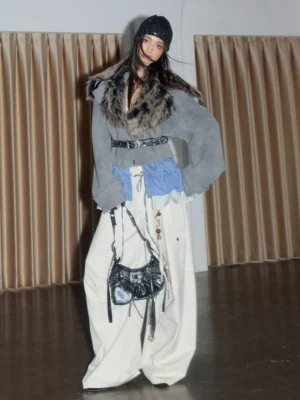 Full-body streetwear styling of a gray cropped jacket with plush faux fur shawl collar blue pleated hem wide belt and white cargo pants