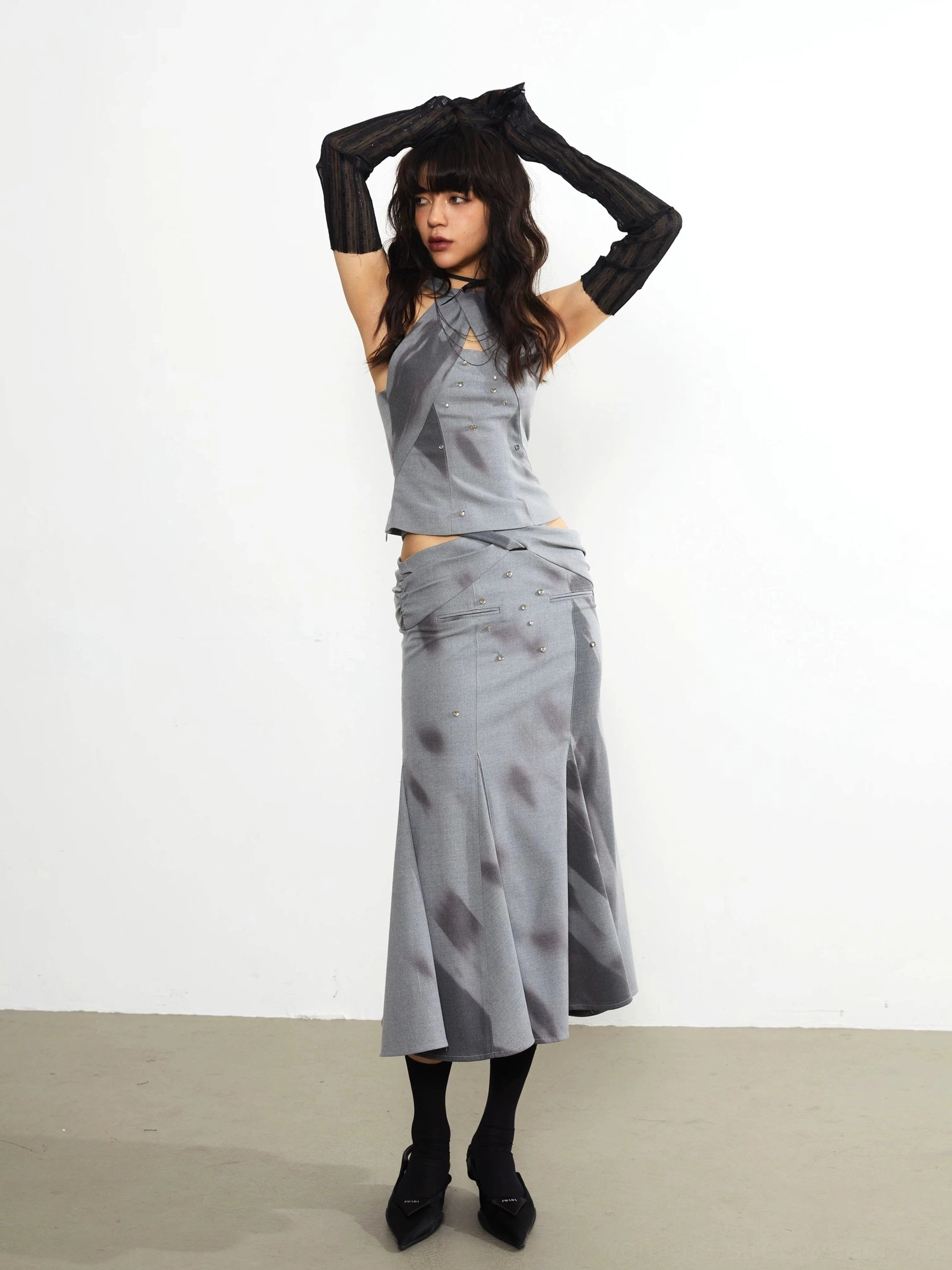 Gray abstract print fishtail midi skirt styled with a matching halter top, black long gloves, and pointed heels