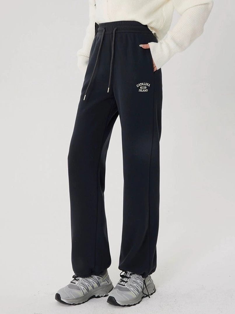 Full-body side view of gray fleece-lined straight-leg streetwear sweatpants with a relaxed wide silhouette, white top, and outdoor sneakers