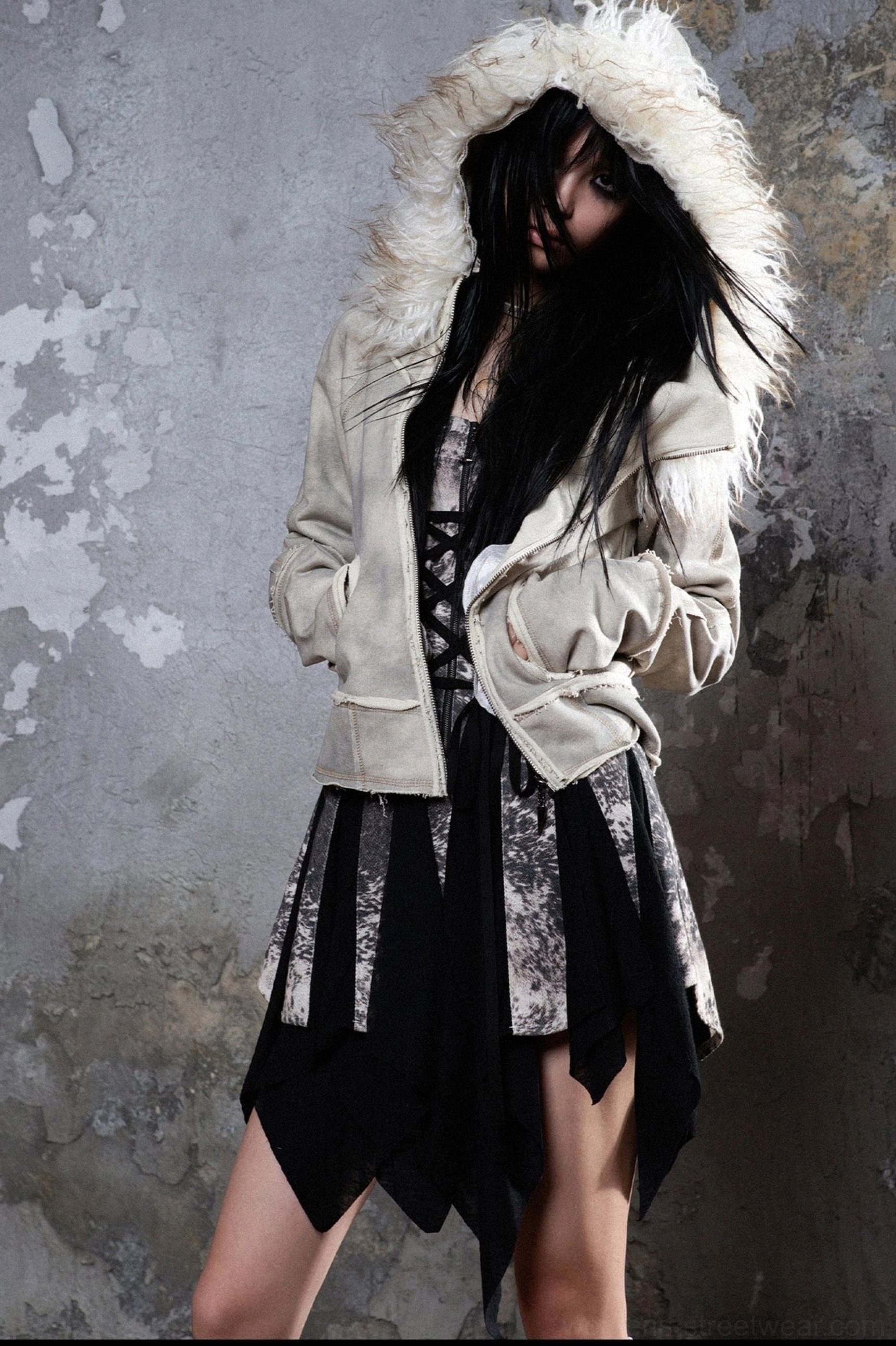 Gray furry-trimmed hooded zip jacket low-angle full view with raw seams, front pockets, and layered black streetwear skirt