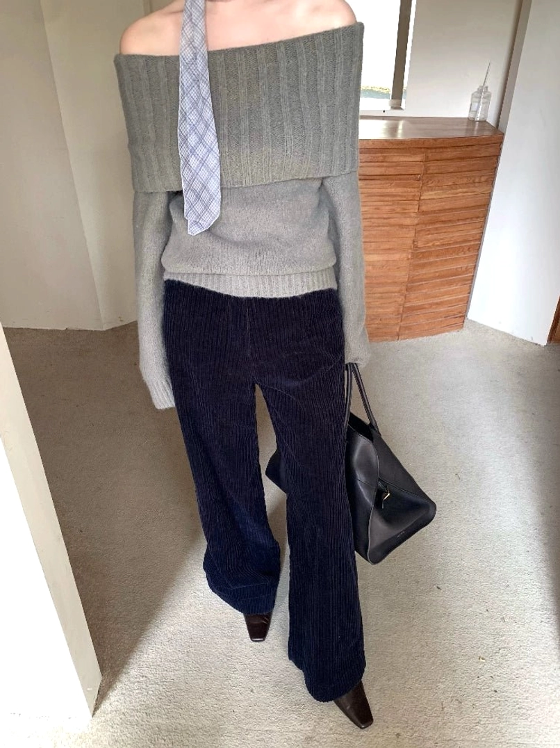 Gray-green fold-over off-shoulder knit sweater styled with dark trousers and a large leather tote bag for city streetwear