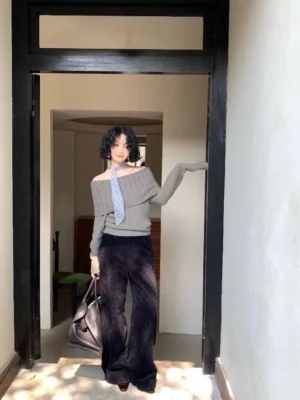 Gray-green women's off-shoulder knit sweater with wide fold-over neckline styled with dark corduroy trousers in a Korean casual look