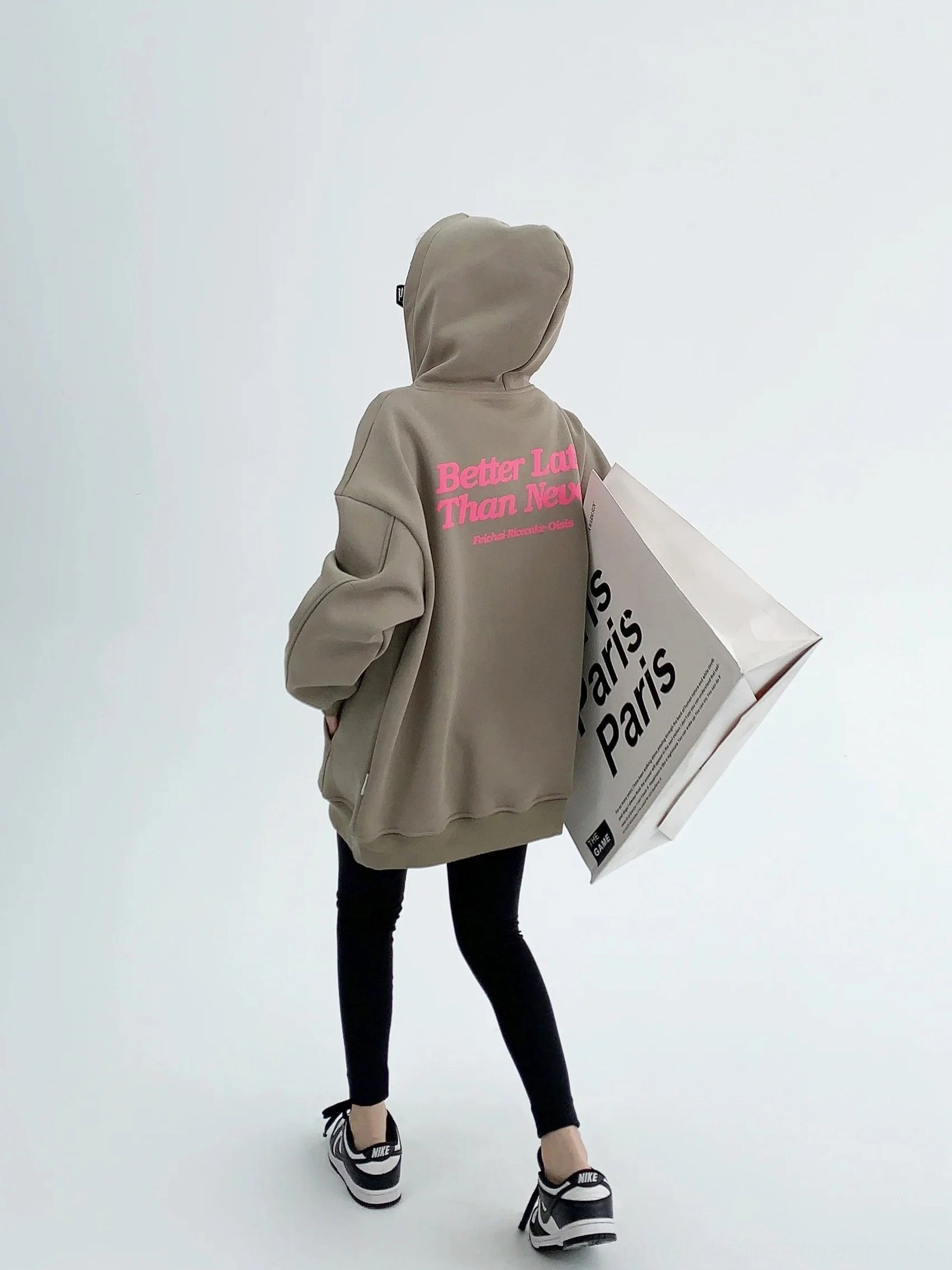 Gray green oversized graphic hoodie full rear view showing complete pink Better Late Than Never back print with black leggings and sneakers