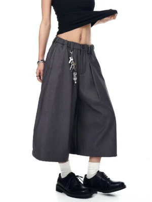 Gray keyring pleated wide-leg culotte trousers shown from a front three-quarter view with cropped hems, belt loops, and utility metal keychain detail