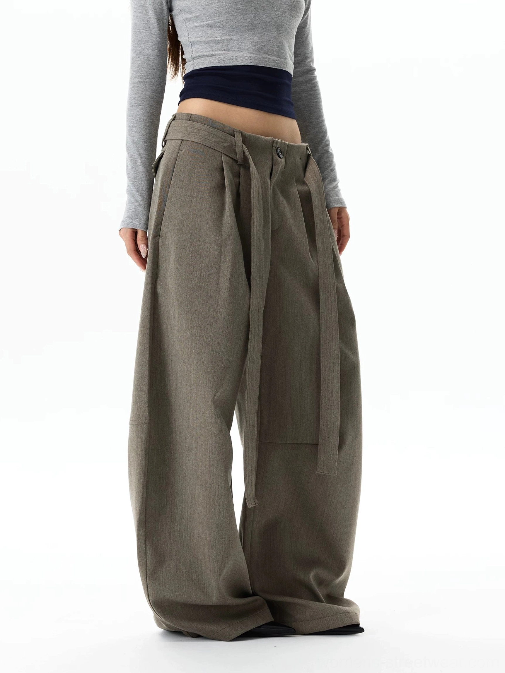 Side rear view of gray khaki avant-garde balloon trousers with long waist sashes, sculptural wide legs, and full-length hems grazing the floor