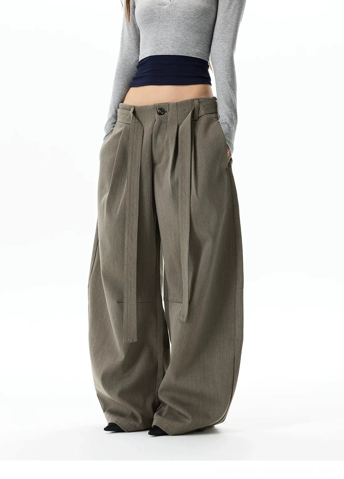 Front side three-quarter view of gray khaki oversized balloon trousers with button fly, layered waistband straps, and flowing relaxed drape