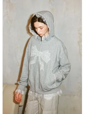 Gray lace bow zip-up hoodie styled with light gray cargo pants and chunky silver sneakers, hood up with white lace trim and romantic bow detail