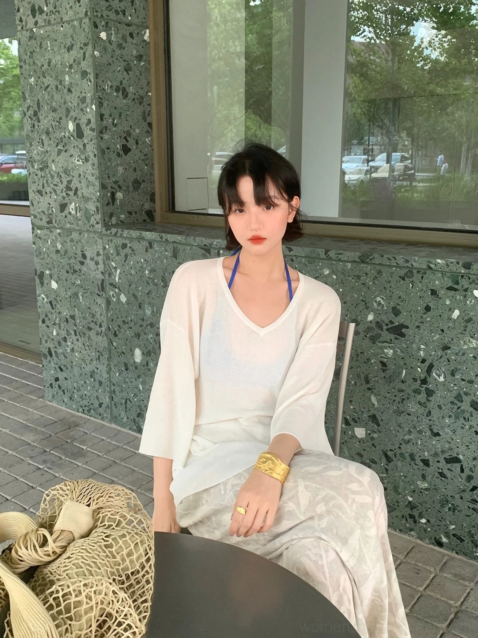 Gray leaf print wide leg streetwear pants paired with a loose white V-neck knit top and woven bag