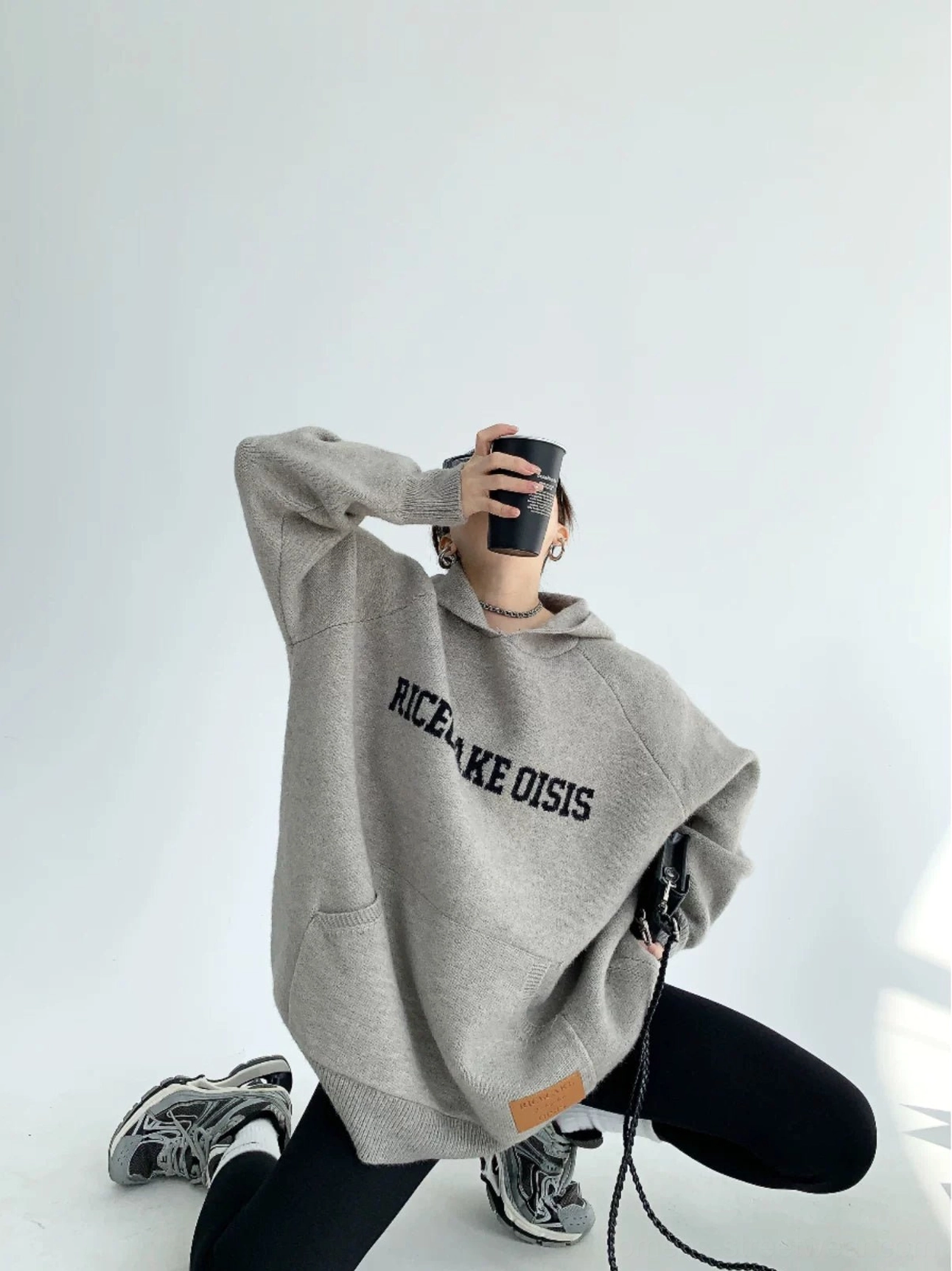 Gray oversized graphic knit hoodie with ribbed trims, kangaroo pocket, leather hem patch, and relaxed casual fit
