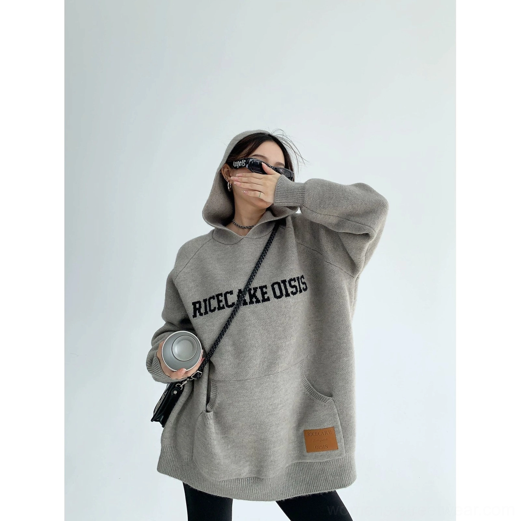 Gray oversized knit hoodie with bold contrast graphic, plush warm texture, ribbed cuffs, kangaroo pocket, and casual styling