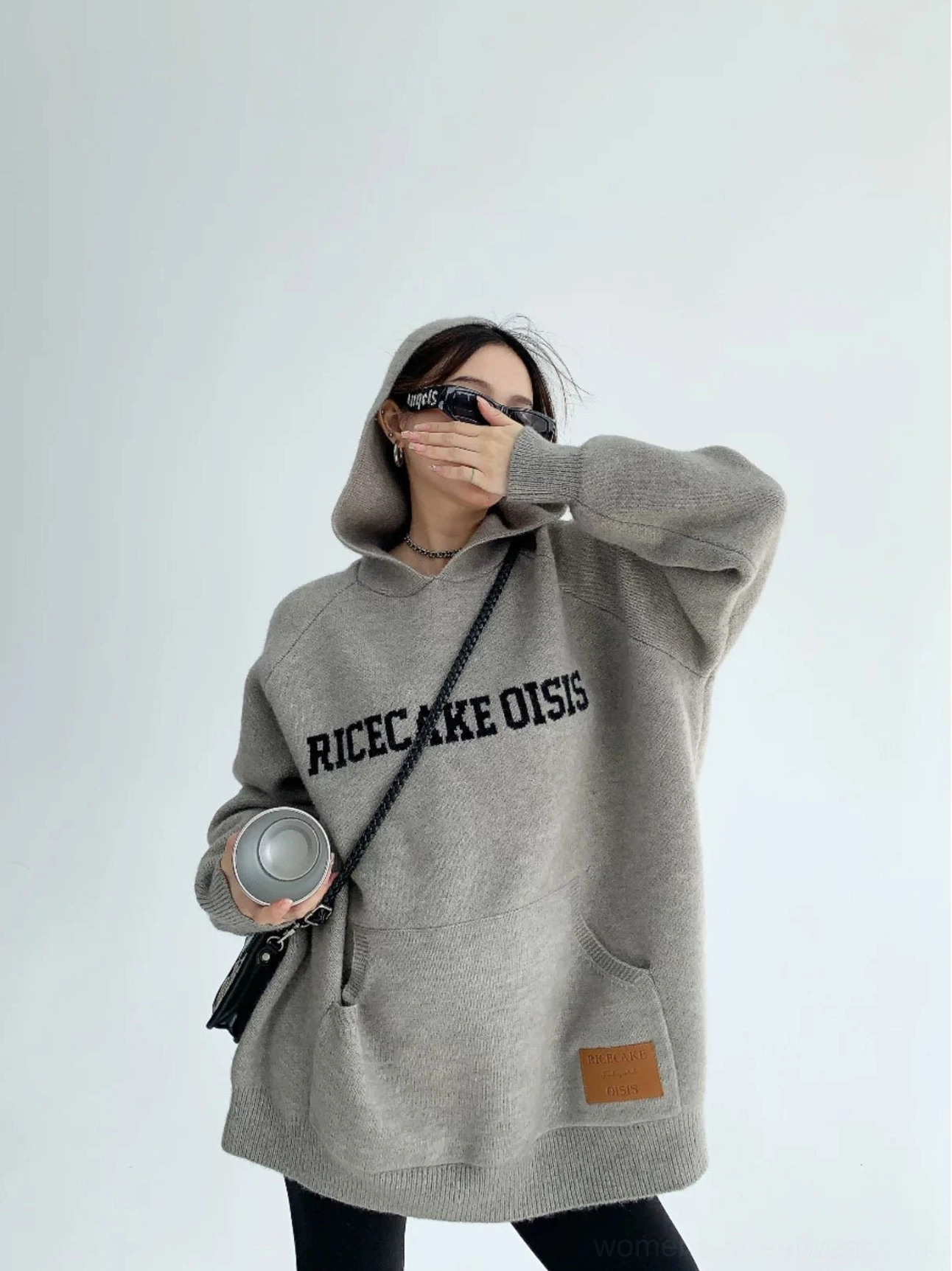 Gray oversized knit hoodie with bold front lettering, soft textured fabric, hood, kangaroo pocket, and leather hem tag