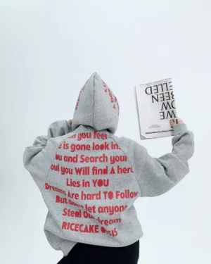 Oversized gray streetwear hoodie shown from the back with red hood and back lettering in a Korean fashion studio scene