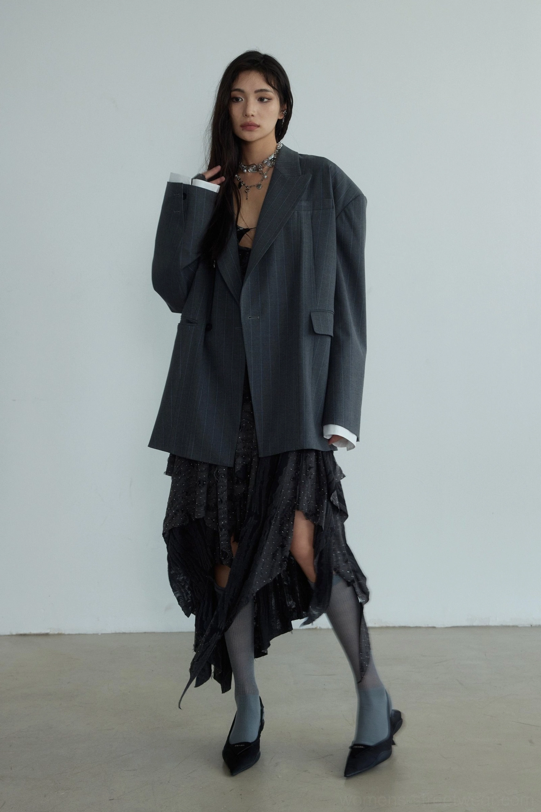 Gray oversized striped blazer with contrasting white cuff lining styled with an irregular ruffled skirt and pointed low heels
