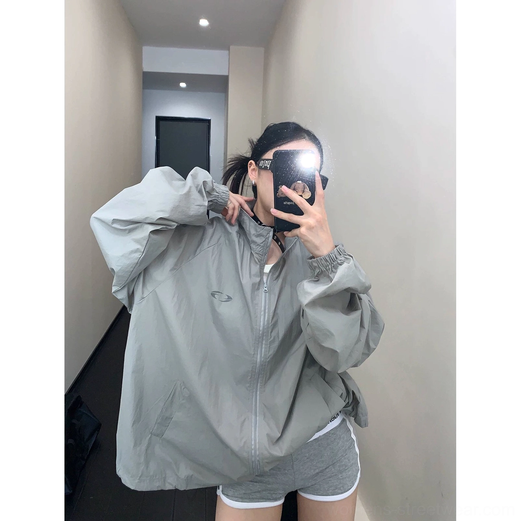 Gray oversized windbreaker jacket product image with subtle geometric logo detail, breathable lightweight fabric, relaxed fit, and versatile urban styling