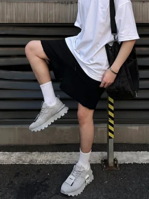 Gray perforated leather platform streetwear shoes styled with white T-shirt black shorts crew socks and shoulder bag on an urban Seoul-inspired street