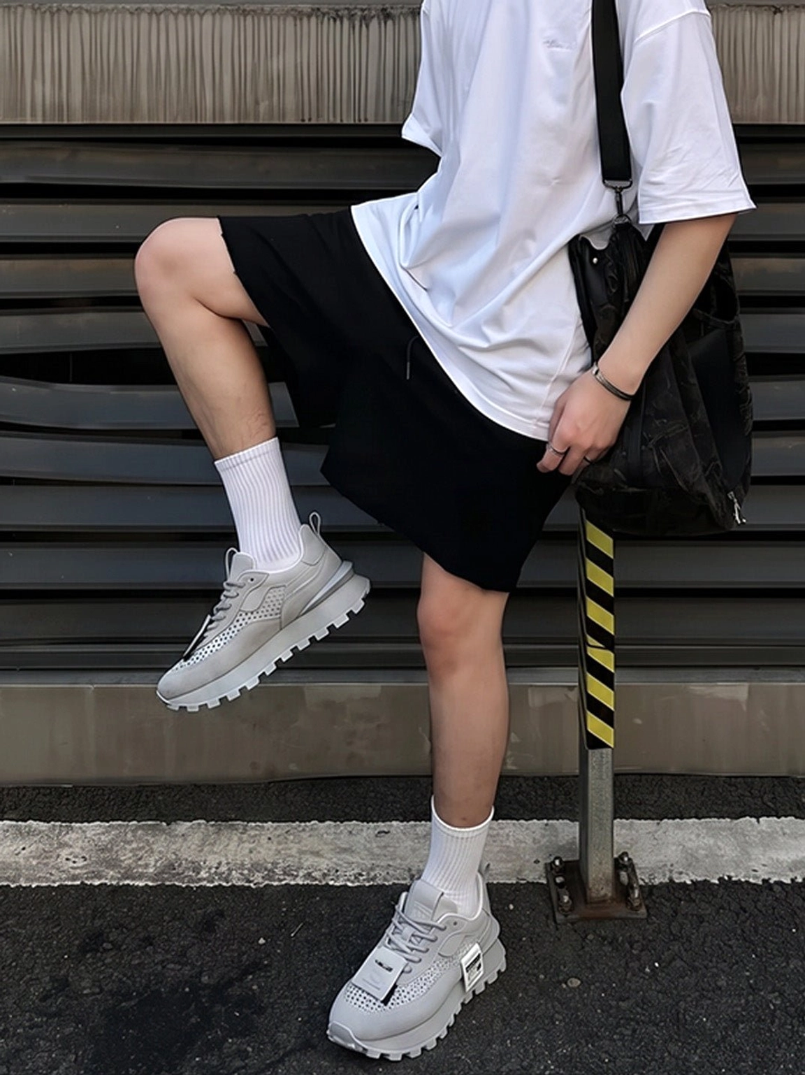 Gray perforated leather platform streetwear shoes styled with white T-shirt black shorts crew socks and shoulder bag on an urban Seoul-inspired street