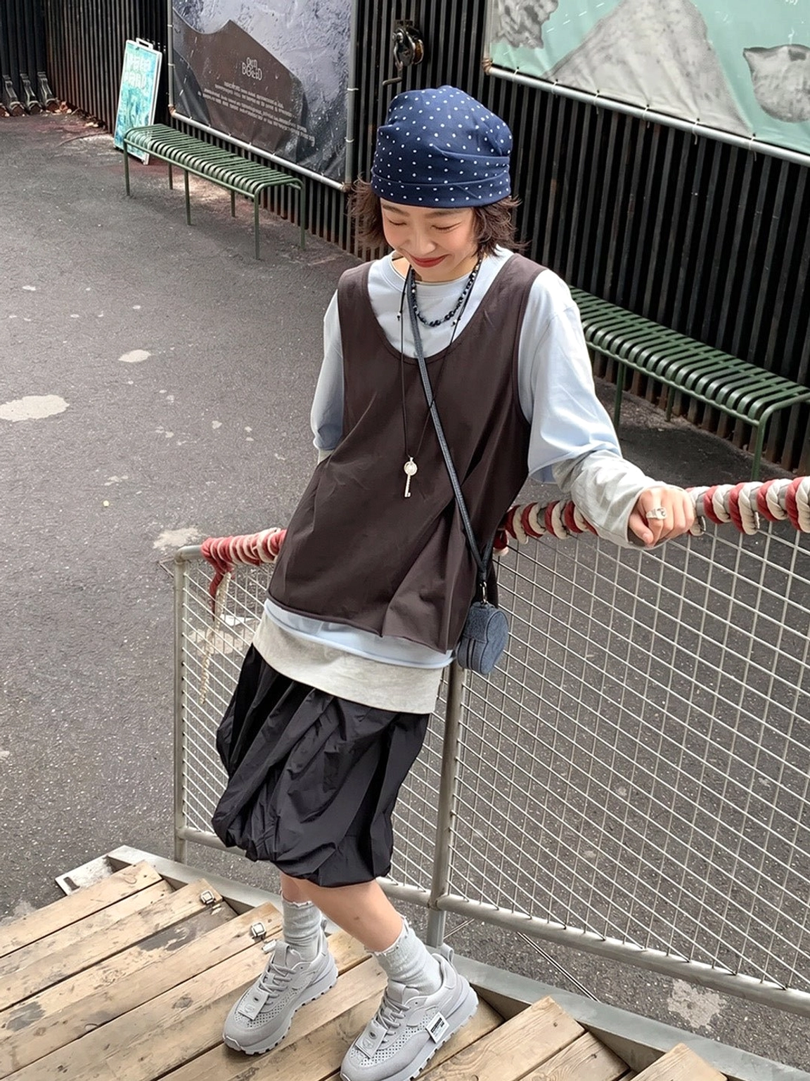 Side view of gray perforated leather platform shoes styled with layered East Asian streetwear clothing on an outdoor walkway