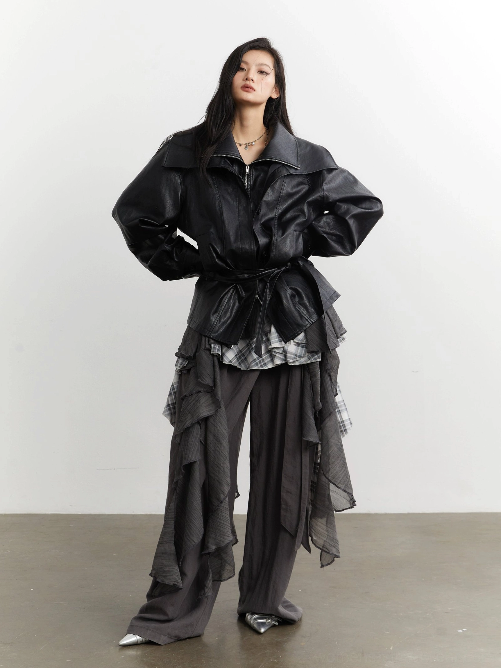 Front styled look featuring gray plaid ruffle deconstructed layering beneath a black belted leather jacket