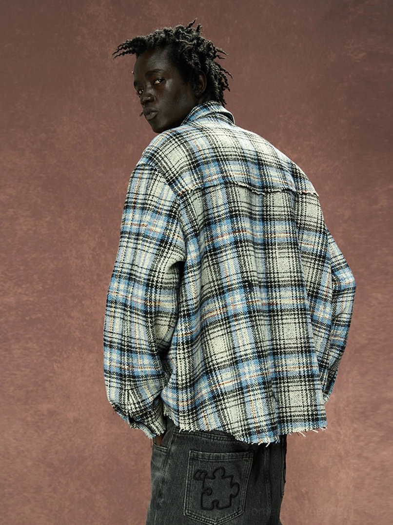 Back three-quarter view of oversized gray plaid shirt jacket showing relaxed fit, tartan pattern, and raw frayed hem