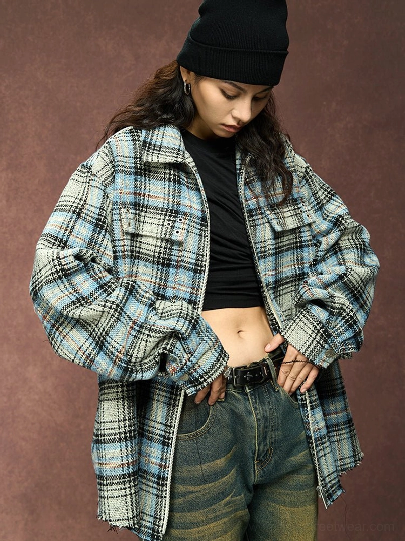 Female model styling a gray plaid zip-up shirt jacket open over a black crop top with vintage wash jeans and black beanie