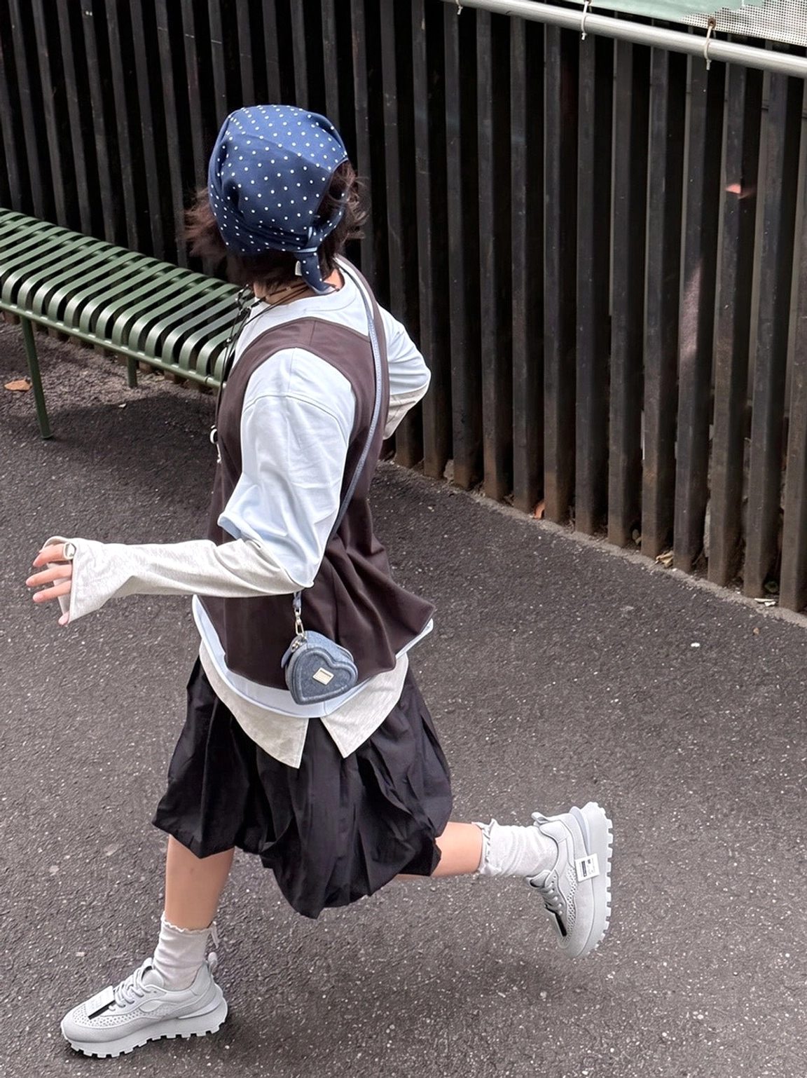Gray platform casual shoes worn with a bandana brown vest white long-sleeve top and black pleated skirt in an urban streetwear look