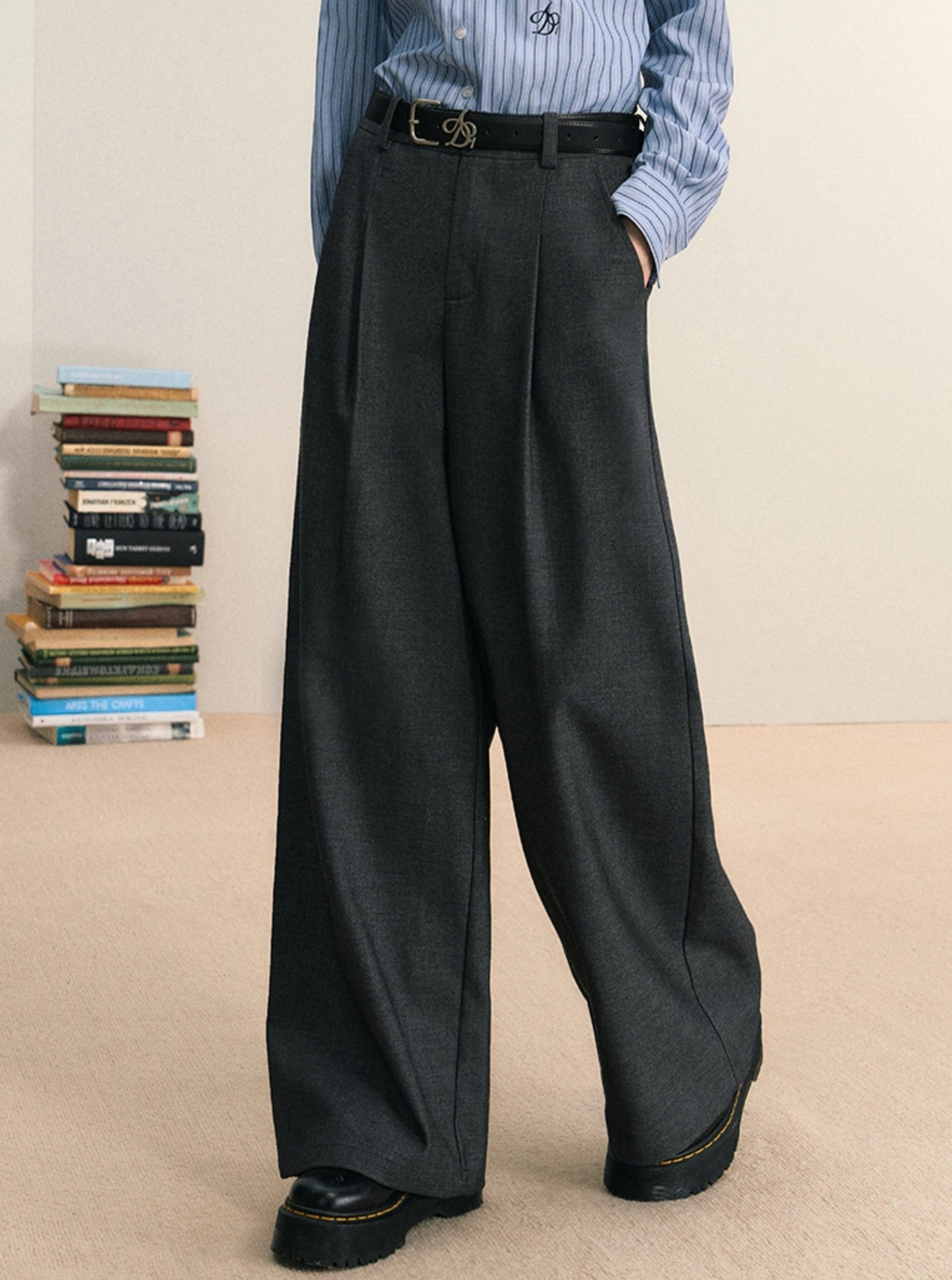 Gray pleated wide-leg streetwear pants worn with a blue striped shirt, black leather belt, and thick-soled shoes