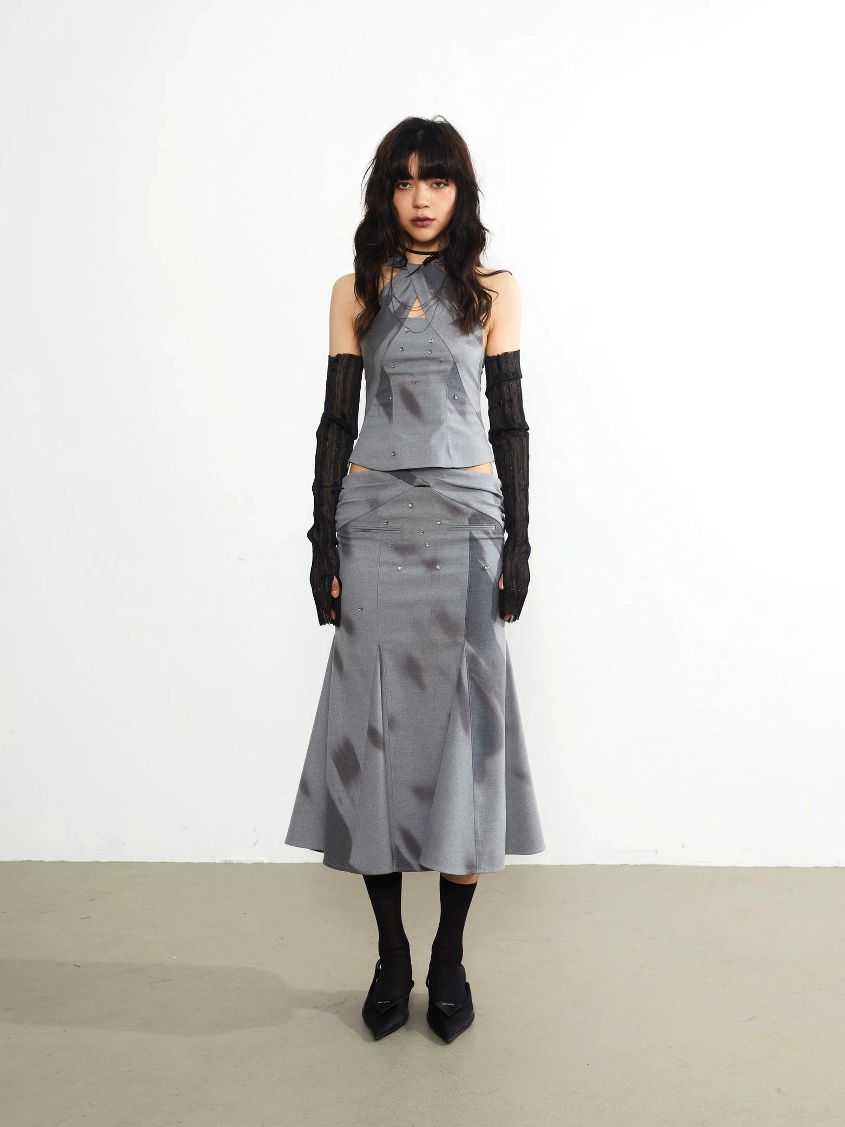 Full front outfit styling with gray printed fishtail midi skirt, matching top, black gloves, and heels