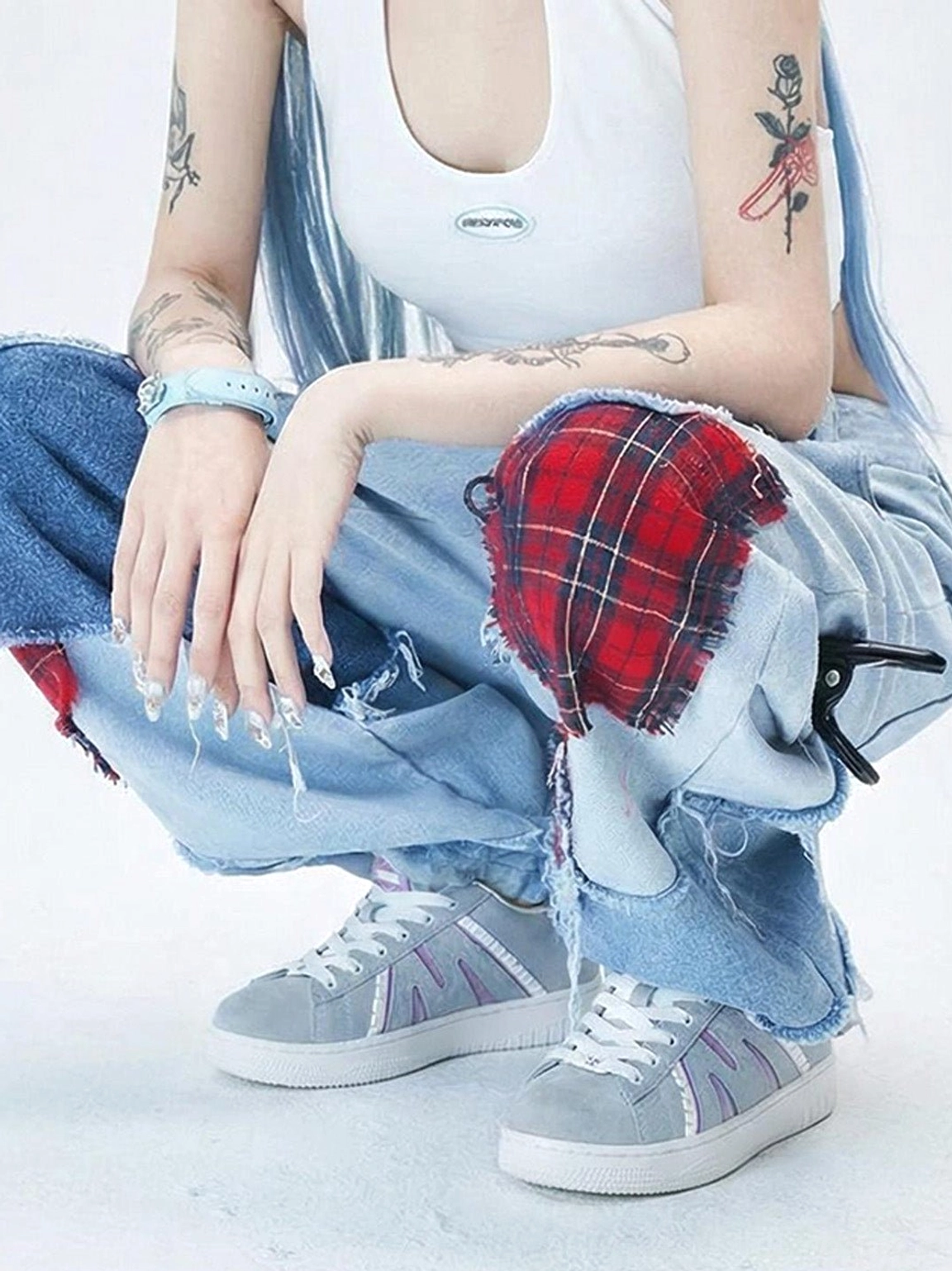 Model wearing gray and purple suede platform sneakers with ripped baggy jeans in a Y2K streetwear look