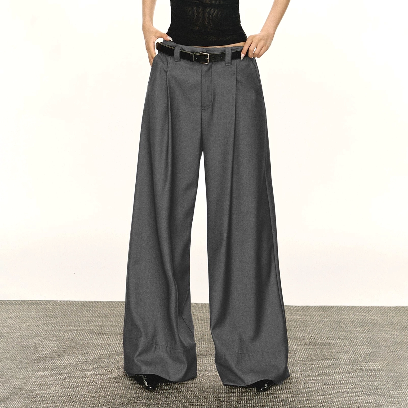Gray retro wide-leg tailored streetwear trousers shown from the front with high-rise pleated waist, belt loops, flowing suiting fabric, and full-length relaxed silhouette