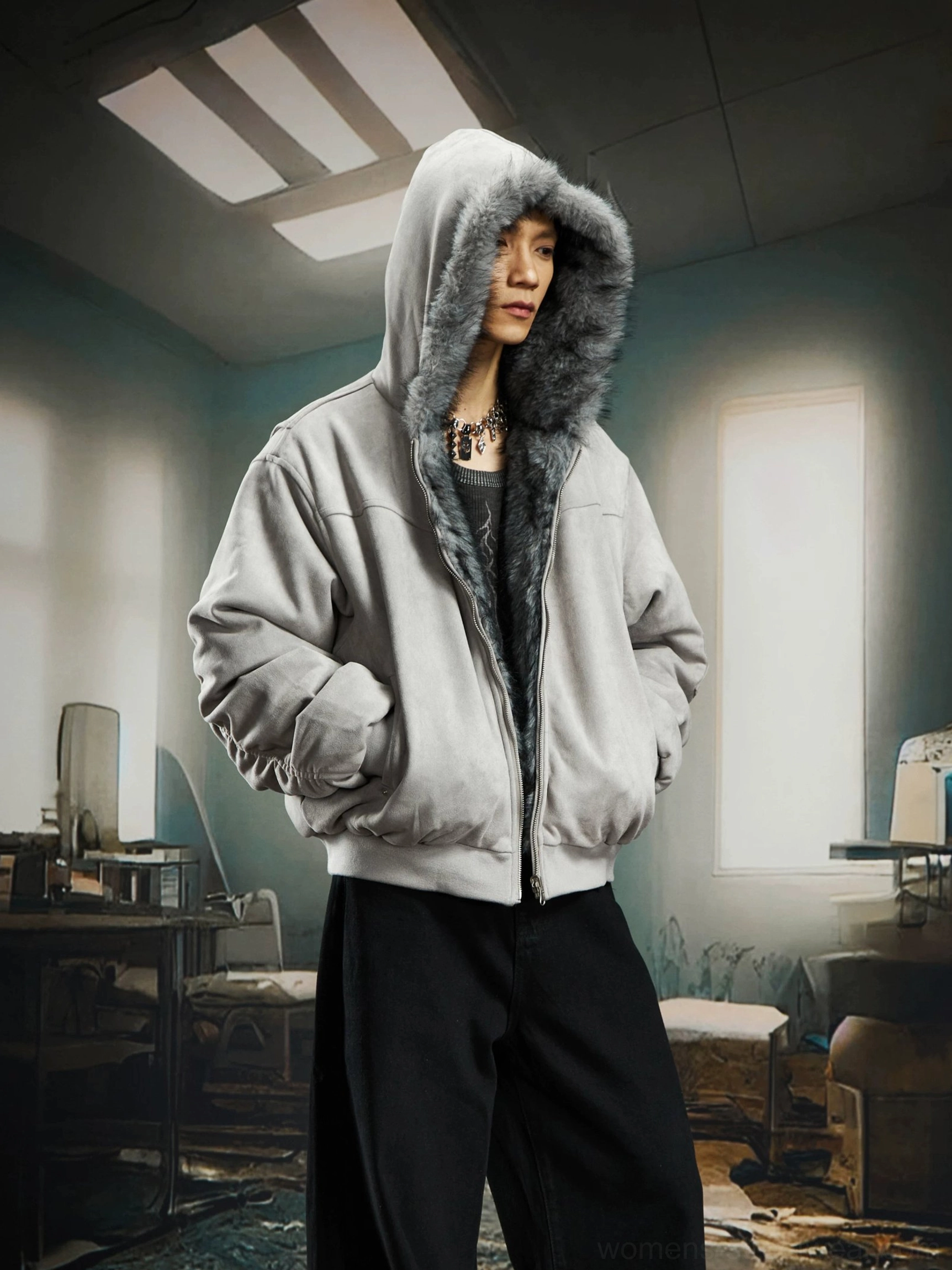 Male model wearing the gray shell side of a reversible faux fur hooded bomber jacket with ribbed bomber trims