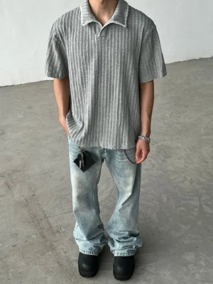 Full body outfit featuring a gray textured ribbed knit polo shirt with baggy light wash jeans and black leather shoes