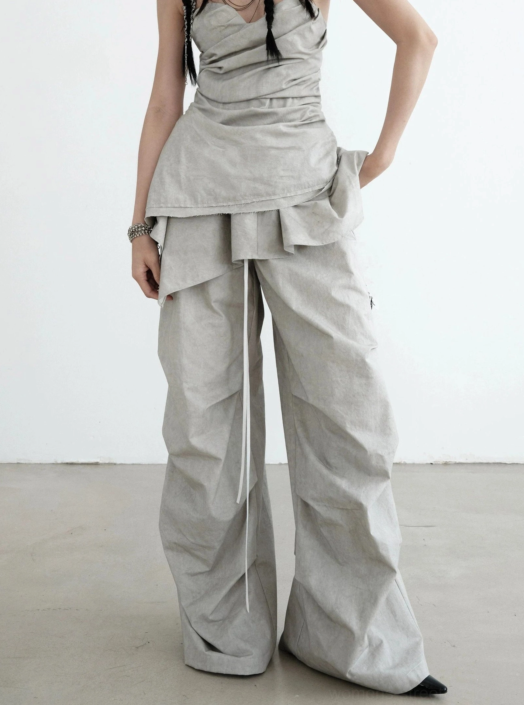 Front view of gray ruffled palazzo cargo pants with drawstring waist, oversized wide legs, crinkled folds, and contemporary Y2K streetwear styling
