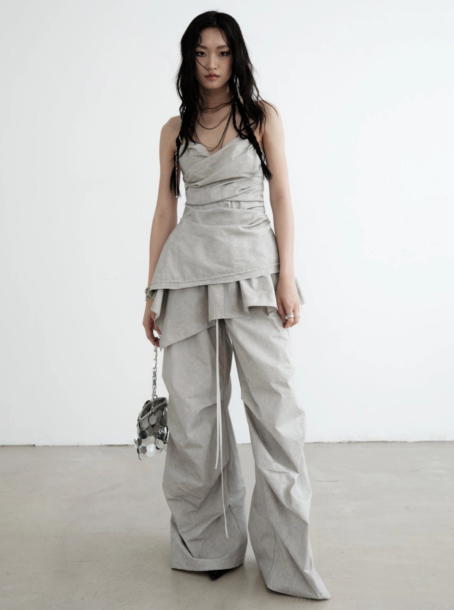 Gray ruffled palazzo cargo pants styled with a ruched camisole and silver handbag in a modern Korean streetwear outfit