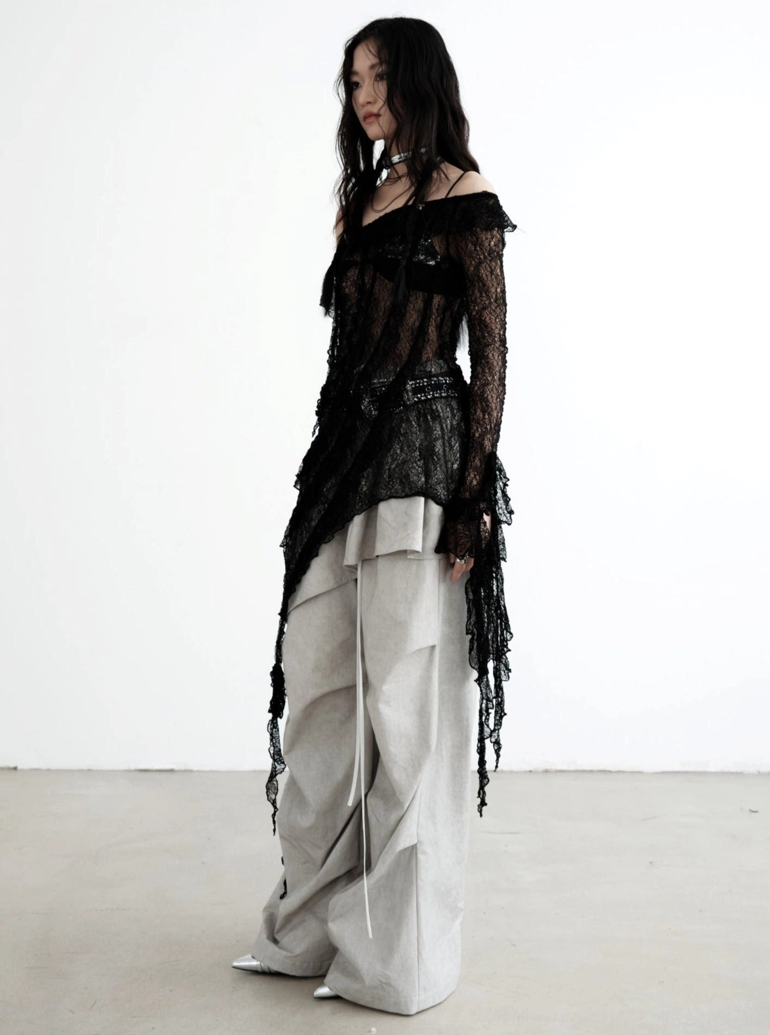 Three-quarter view of gray ruffled palazzo cargo pants with visible drawstring cords and a sheer lace layered streetwear outfit