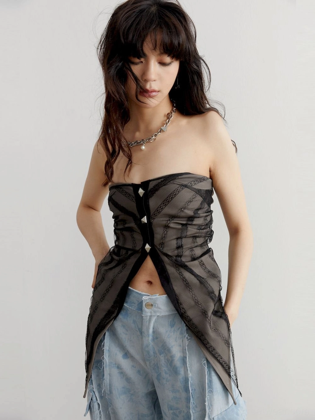 Front detail view of a gray sheer corset-inspired tube top with three pyramid studs and an asymmetric high-low hem