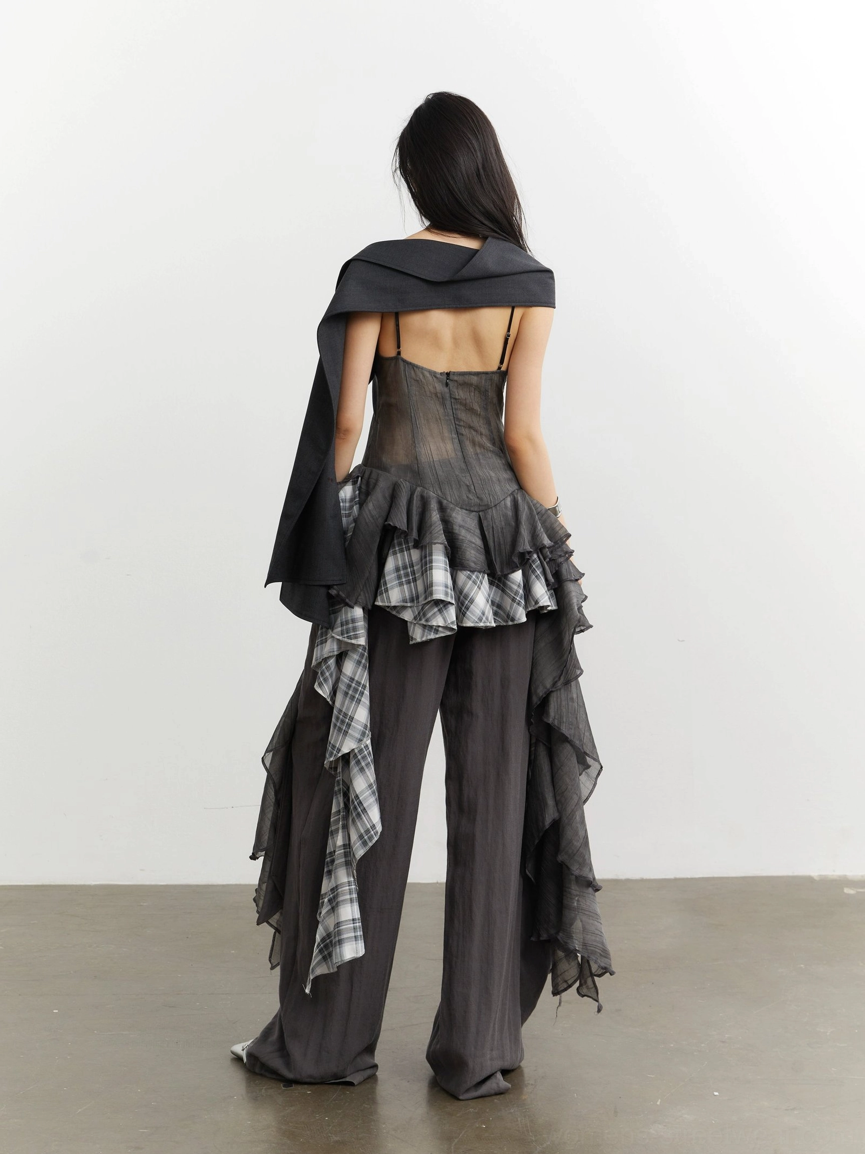 Back view of gray sheer mesh deconstructed camisole top styling showing corset inspired construction and plaid ruffle hem