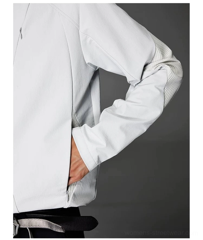 Close-up of gray softshell jacket sleeve and side pocket showing the breathable inner sleeve panel, smooth matte fabric, and concealed zipper pocket