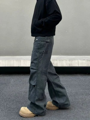 Side view of relaxed gray streetwear cargo pants showing flap cargo pocket, snap fastener, utility stitching, and wide-leg fit