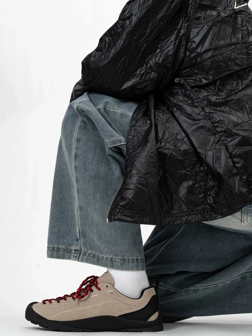 Gray taupe suede low-top trail sneakers with dark red laces and durable black outsole styled with a black quilted jacket and baggy jeans