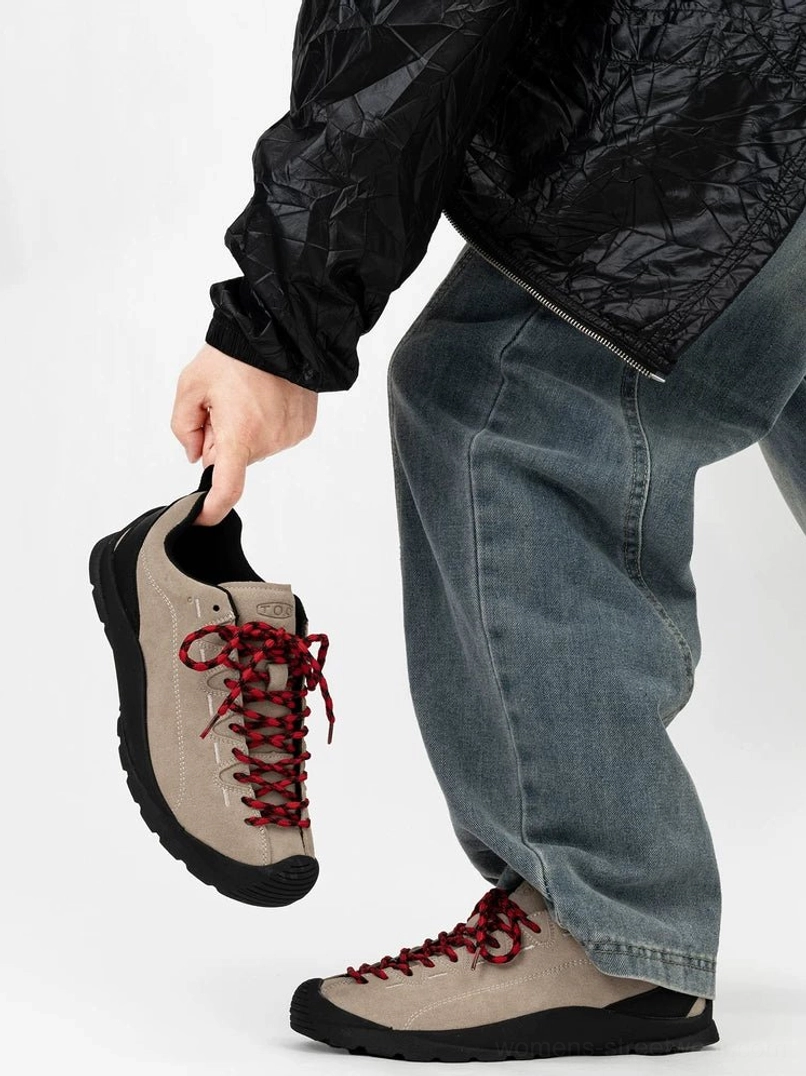 Gray taupe suede trail sneakers with dark red hiking laces and black rubber outsole shown in hand and worn with loose blue jeans