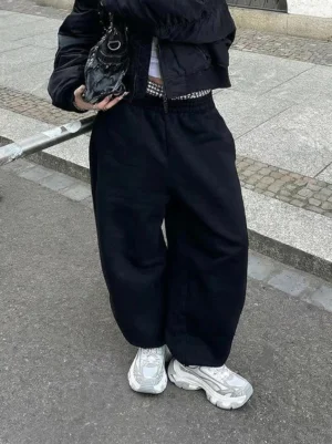 Overhead view gray-teal platform sneakers worn with black oversized streetwear outfit cropped jacket baggy pants urban concrete sidewalk white ankle socks