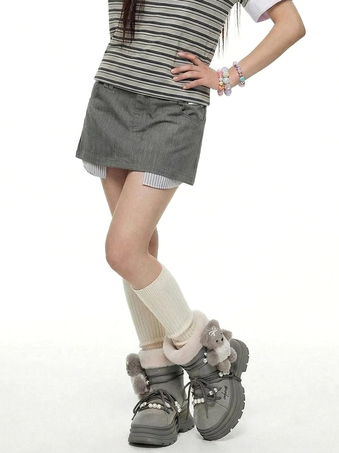 Side view of model wearing gray plush cuff platform snow boots showing chunky soles and teddy bear heel charms