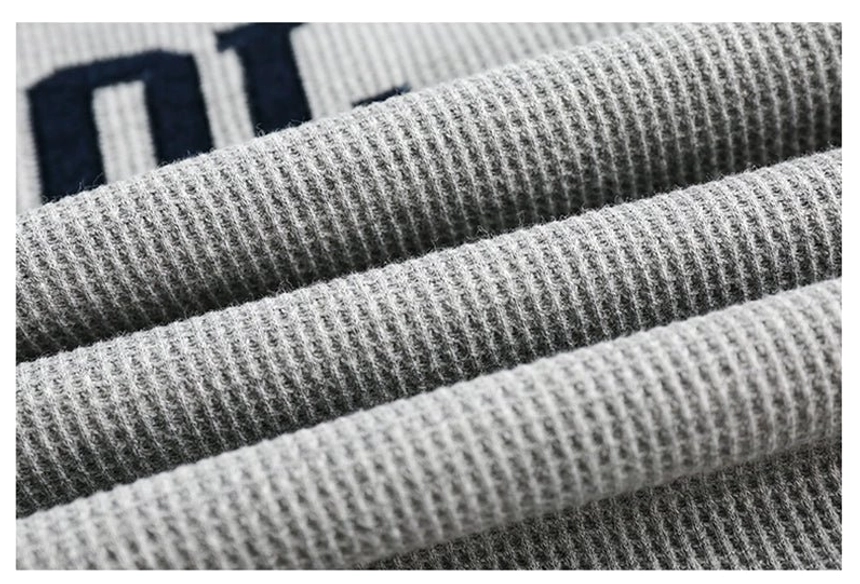 Close-up view of soft gray waffle-knit sweatshirt fabric showing raised grid texture and substantial streetwear material