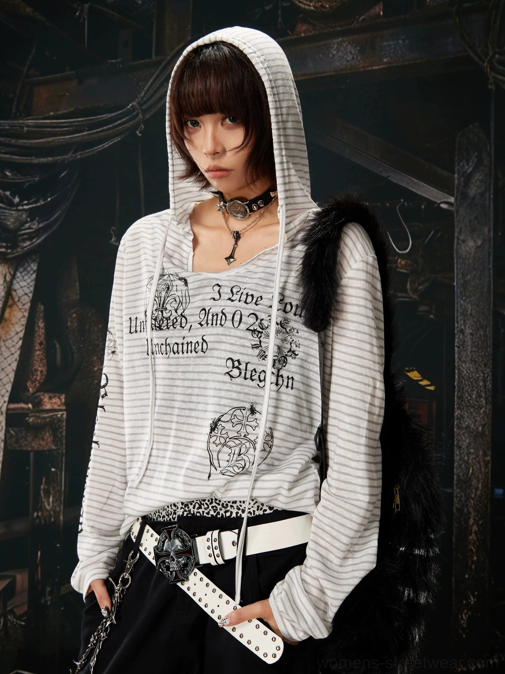 Close-up of a gray and white striped hooded long sleeve streetwear shirt with gothic graphics, silver hardware belt, and alternative styling