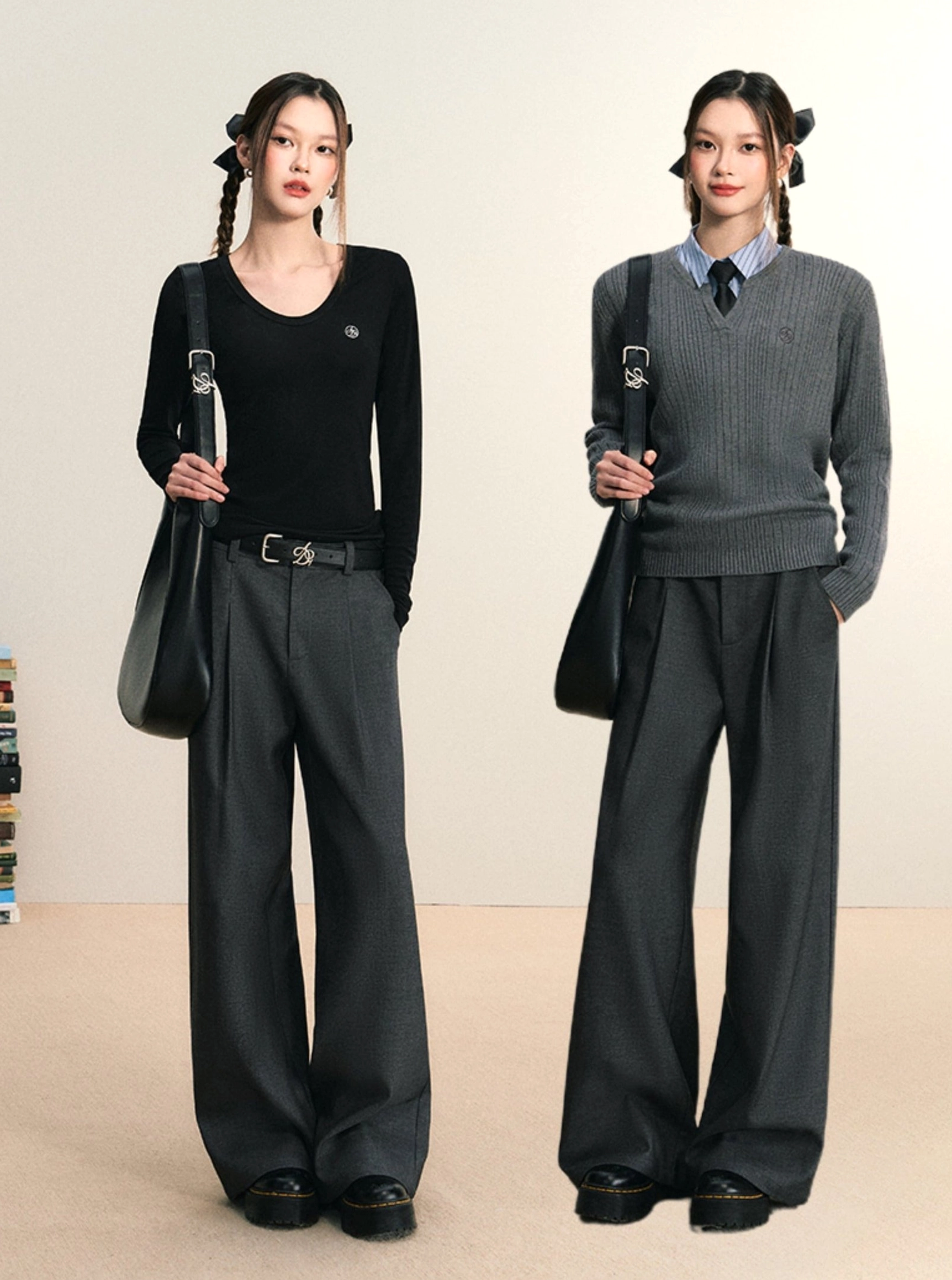 Two models wearing gray wide-leg pleated streetwear trousers with knit tops, black belts, and shoulder bags