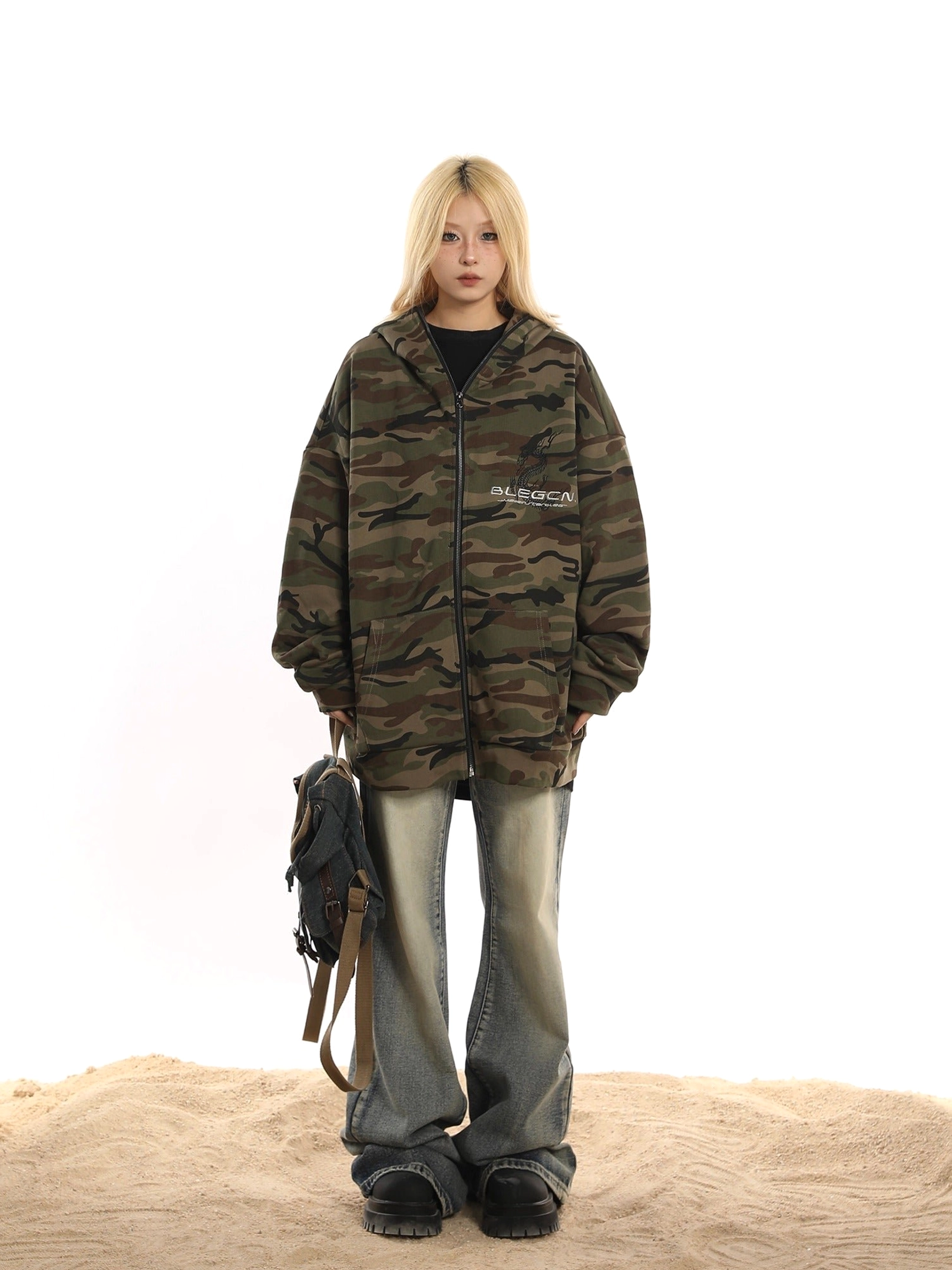 Full-length streetwear outfit featuring an oversized green camo fleece jacket, washed denim, crossbody bag, and platform sneakers