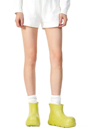 Women's green chunky rain boots styled with white shorts and crew socks showing the elevated platform sole and casual streetwear fit