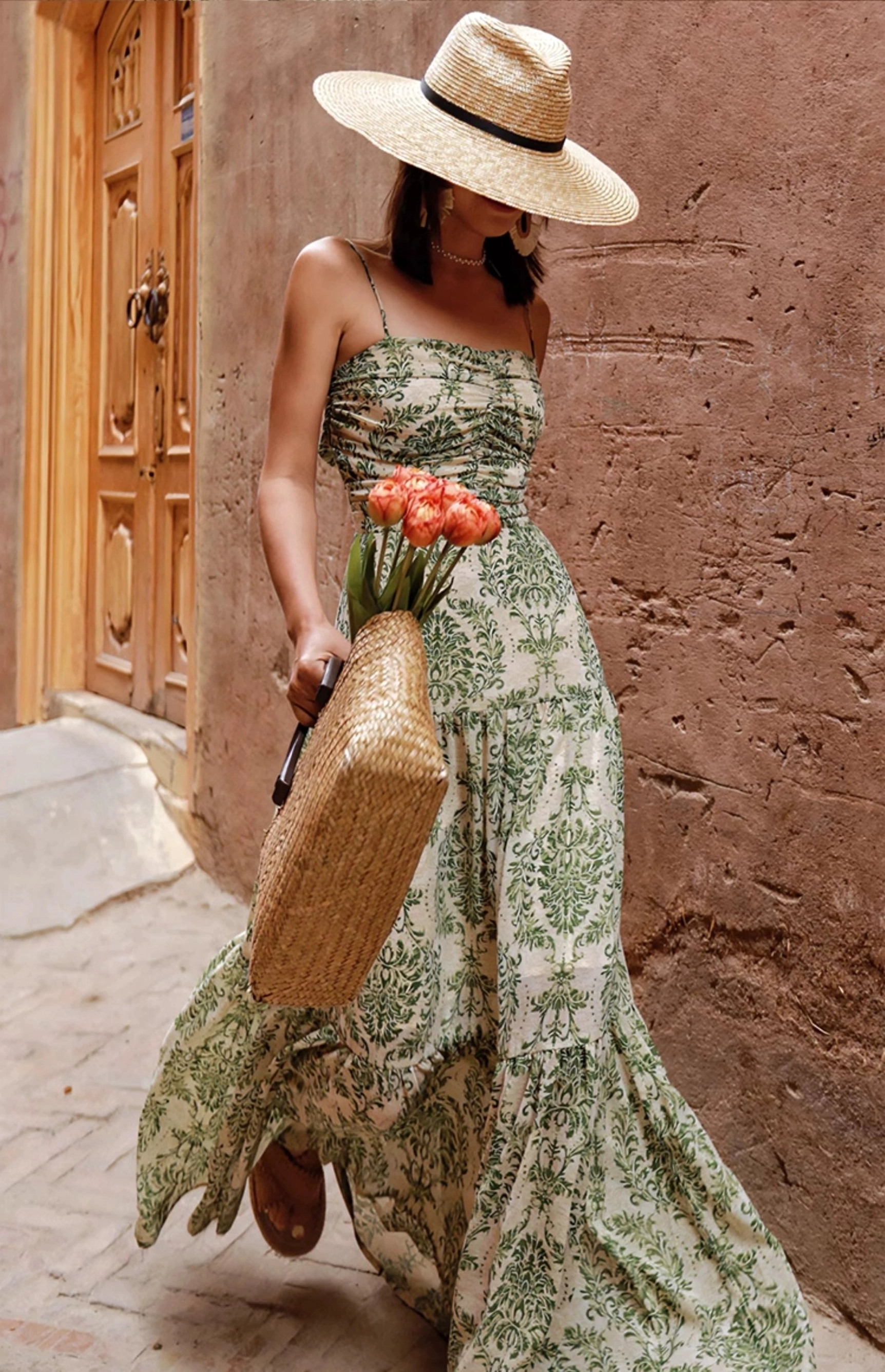 Green floral tiered maxi dress front walking view with adjustable spaghetti straps and flowing ruffled skirt