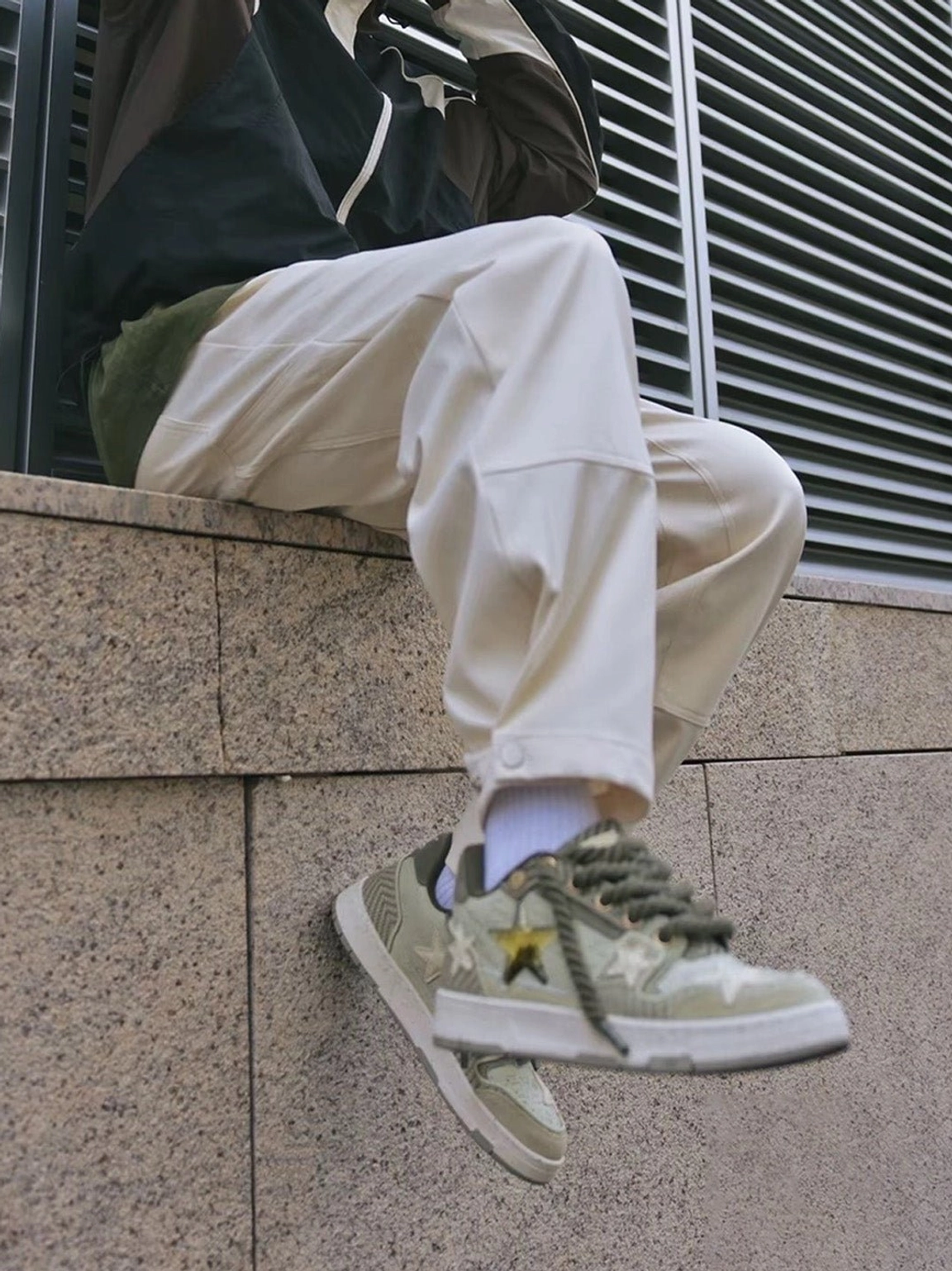 Green Longjing tea star sneakers worn with loose white pants and white socks in an outdoor Seoul-inspired streetwear setting
